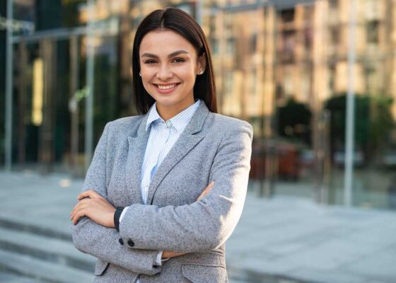 Ex studentessa in tailleur all'esterno di un'azienda sorridente