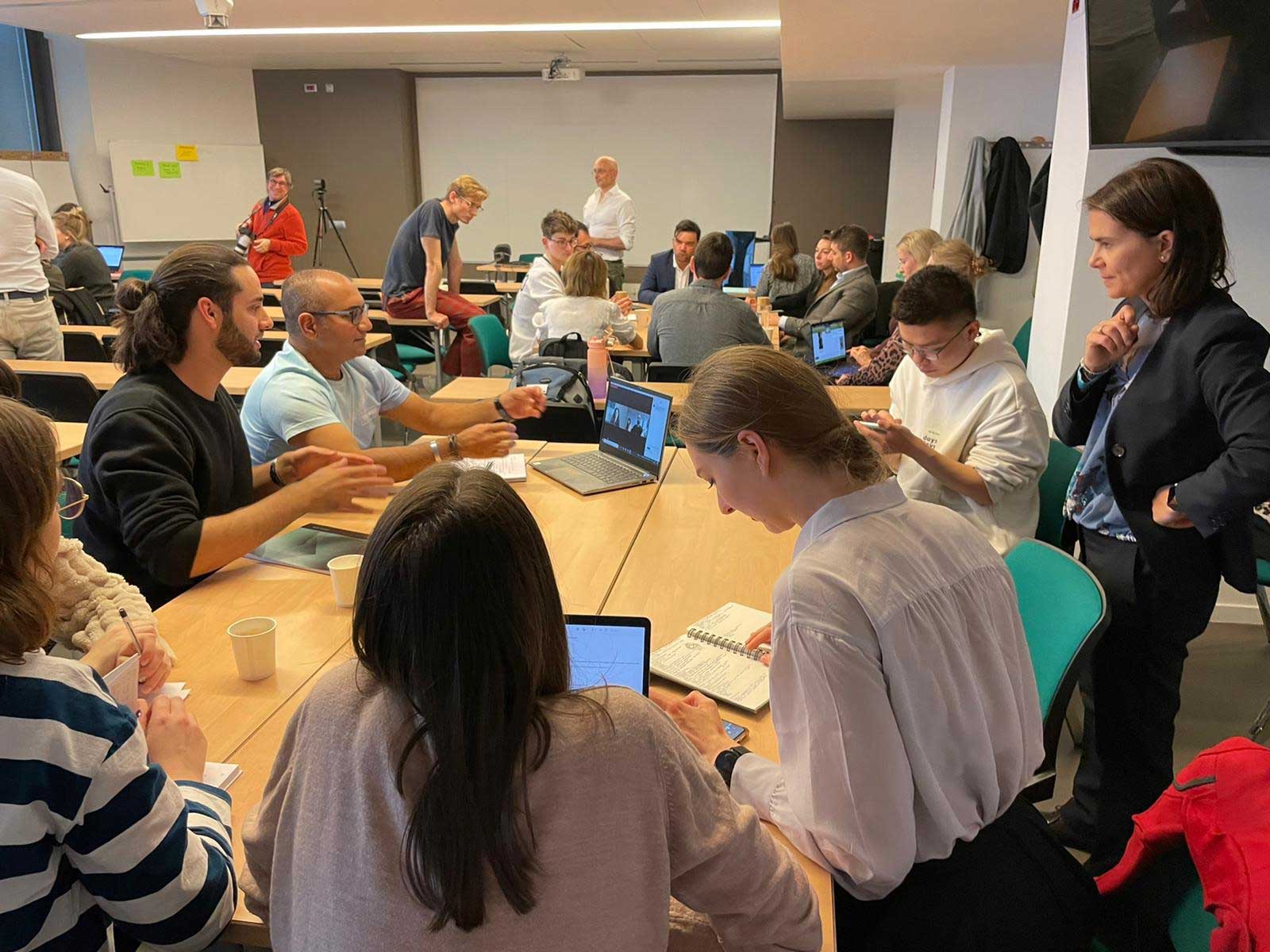 Studenti riuniti con mentor adulti intorno a un tavolo con computer accessi