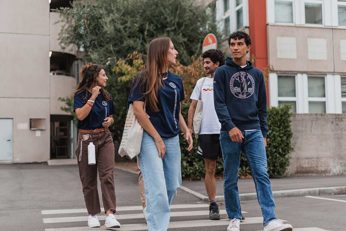 Studenti Unimi che attraversano la strada con indosso degli abiti con il brand della Statale